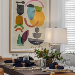 a table with a lamp and a painting on the wall